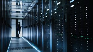 room of computer servers and man checking them