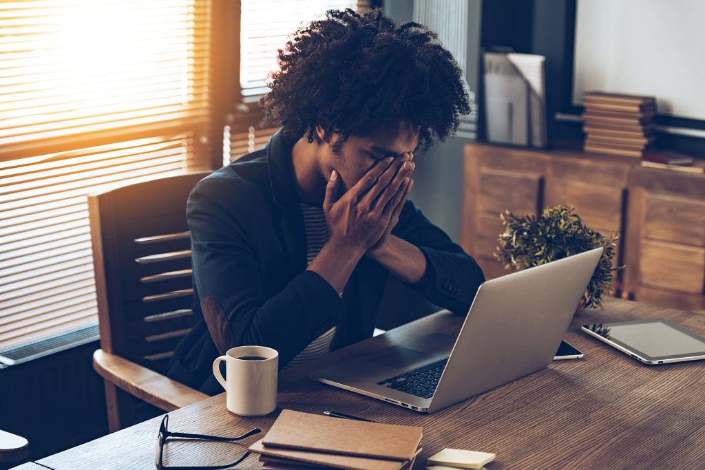 worried man sat at his desk with head in hands